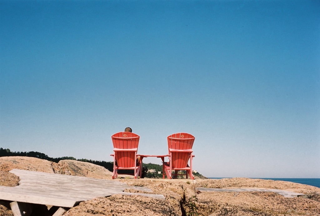 Two red and blue armchairs facing the landscape vastness in Tadoussac.