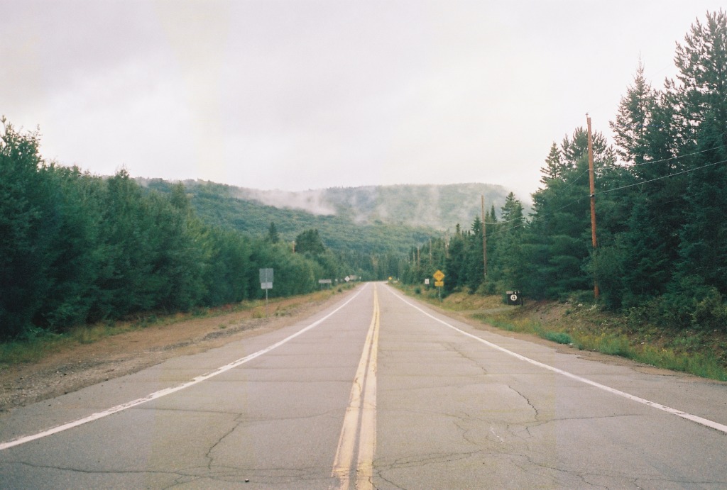 Long straight road crossing a coniferous forest under a grey sky at Mont-Tremblant.