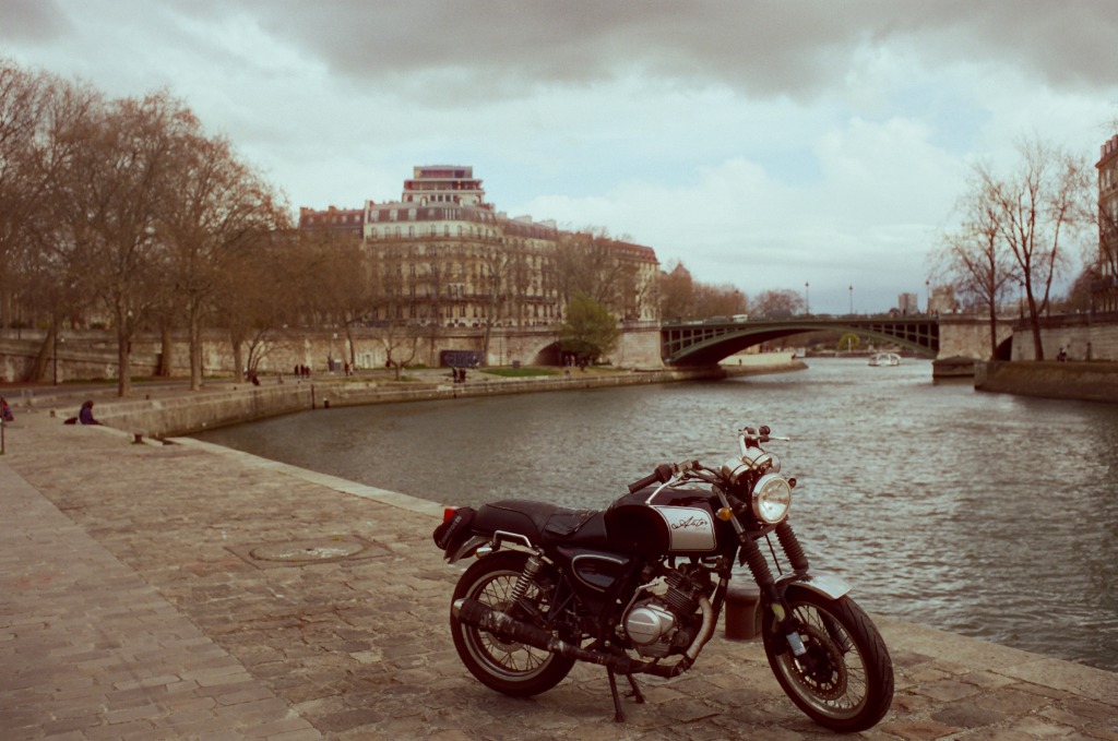 Vintage Astor motorcycle parked on the Seine quay cobblestones.