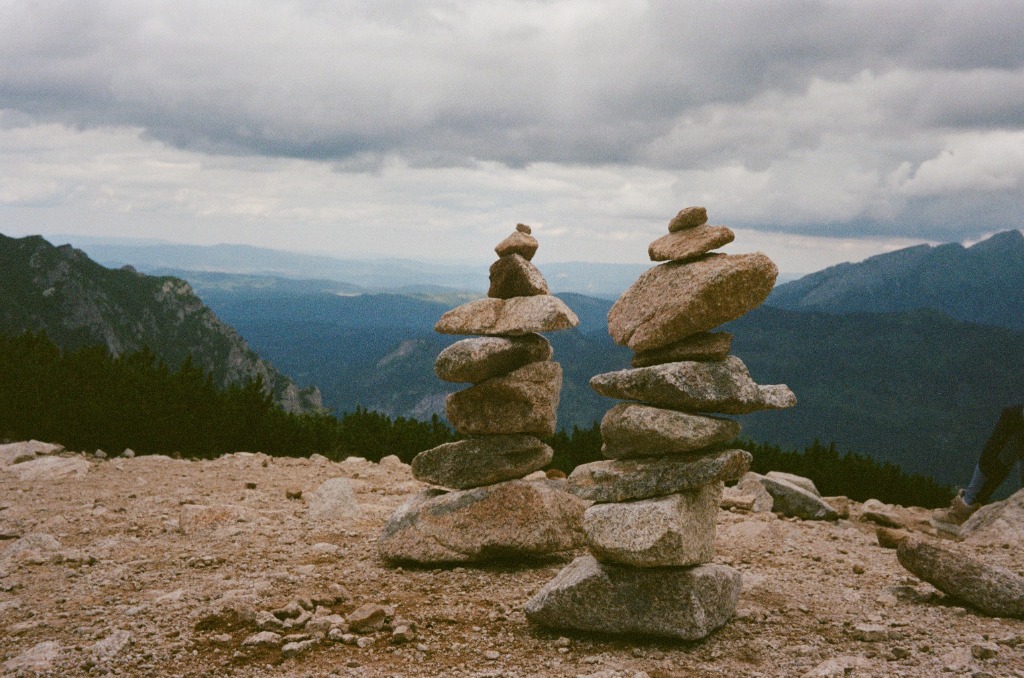 Two small stone cairns in foreground before a vast valley landscape.