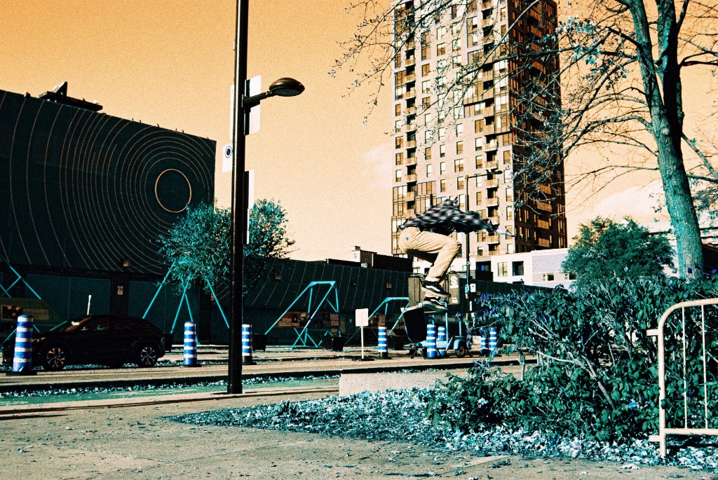 Skater frozen in mid-air jump, electric blue coat and pale sky.