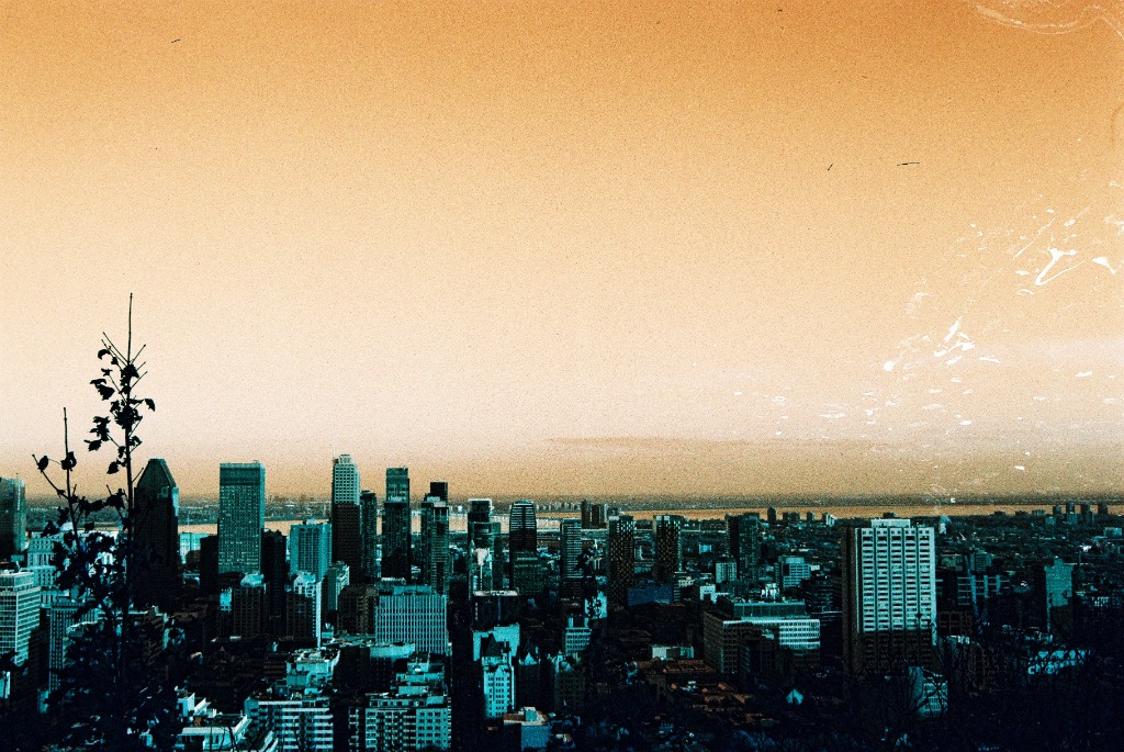 Montreal skyline with orange sky and blue-green towers, LomoChrome infrared film effect.