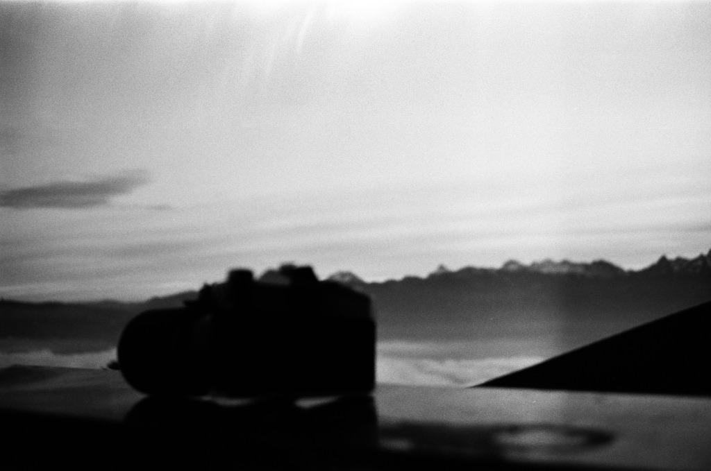 Nikon camera resting on a frosted railing facing a blurred mountain panorama.