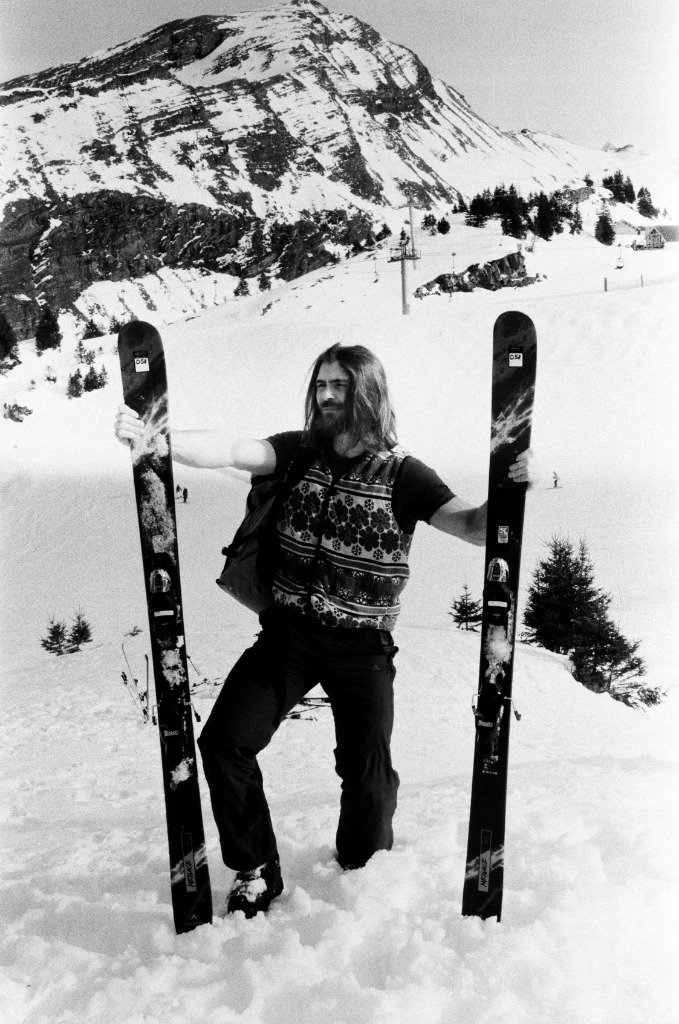 Solitary skier standing three-quarters in the snow, looking at the horizon, contrasted black and white.