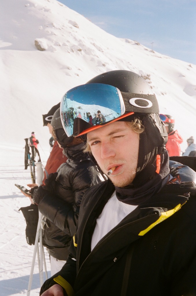 Portrait of a skier with cigarette and goggles reflecting the panorama.