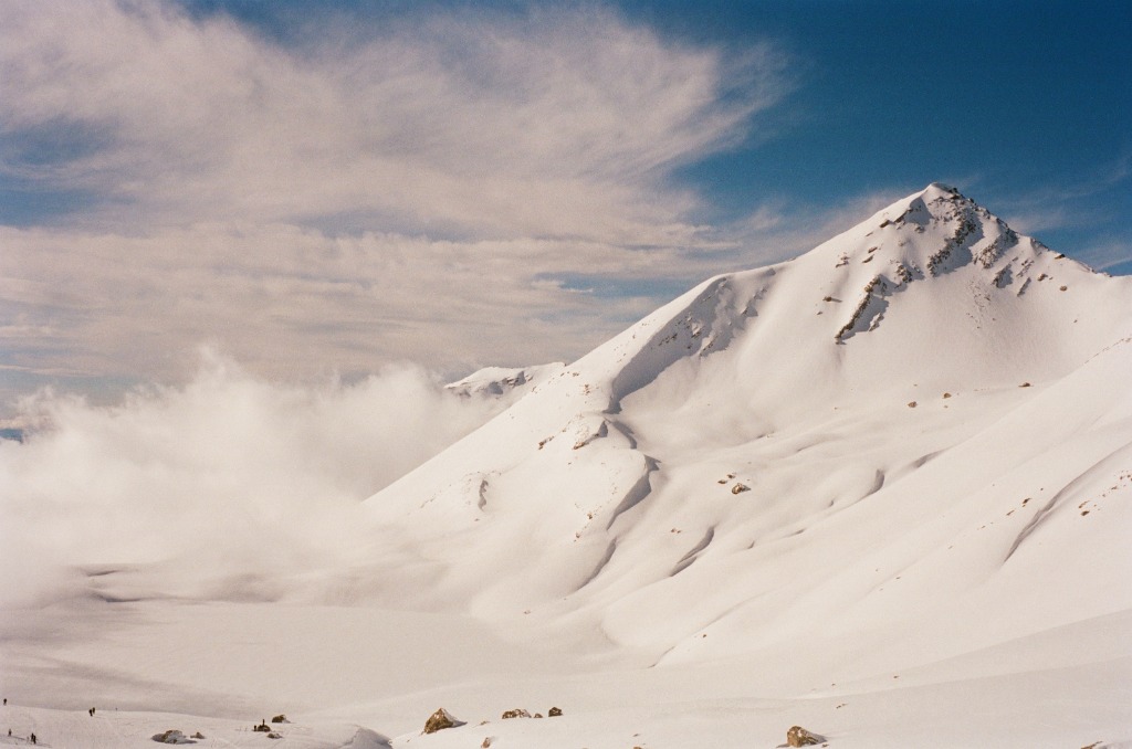 Snowy mountain peak half-hidden by a sheet of fog.