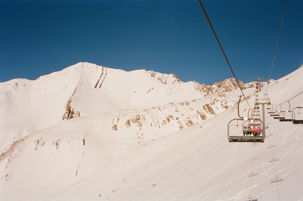 Bird's eye view from a cable car over snowy slopes and deep blue sky.