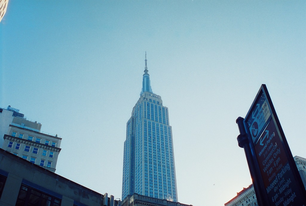 Empire State Building seen from a low angle, splitting a pale blue sky.