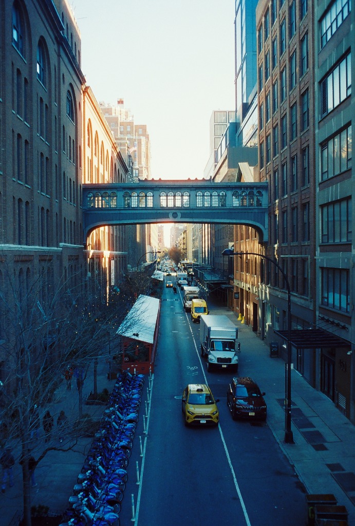 High angle view from the High Line onto an avenue, with a yellow taxi.