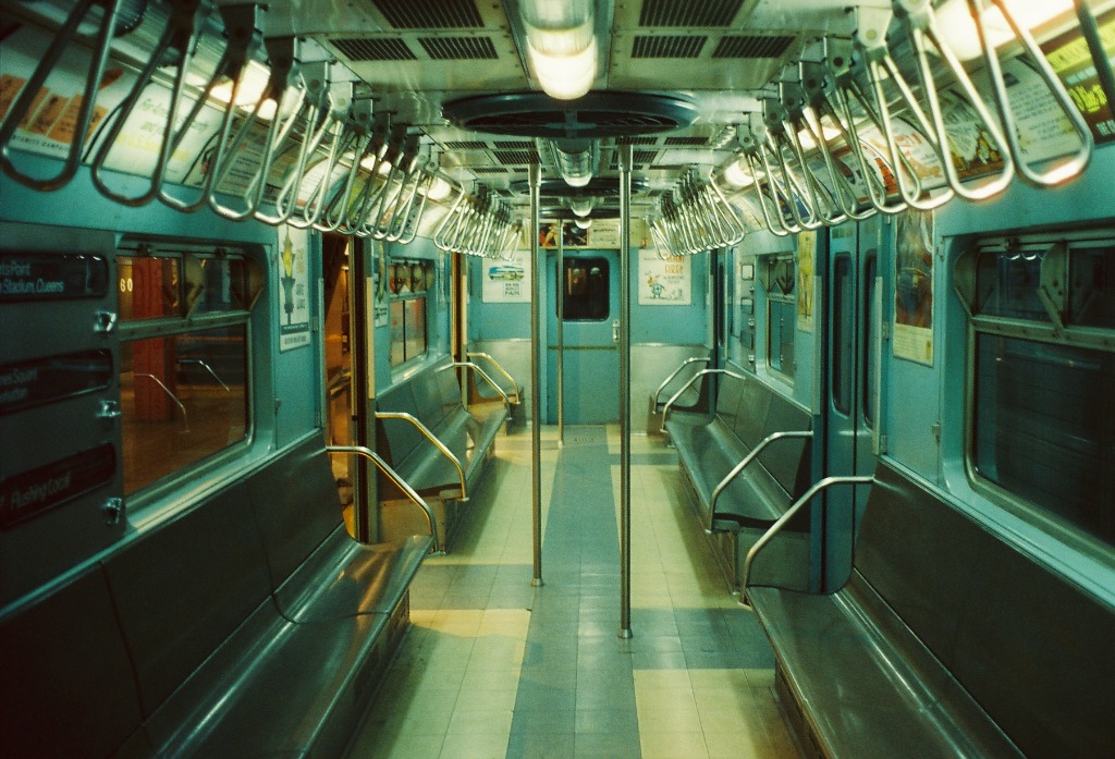 Interior of an empty New York subway car with neon lighting.